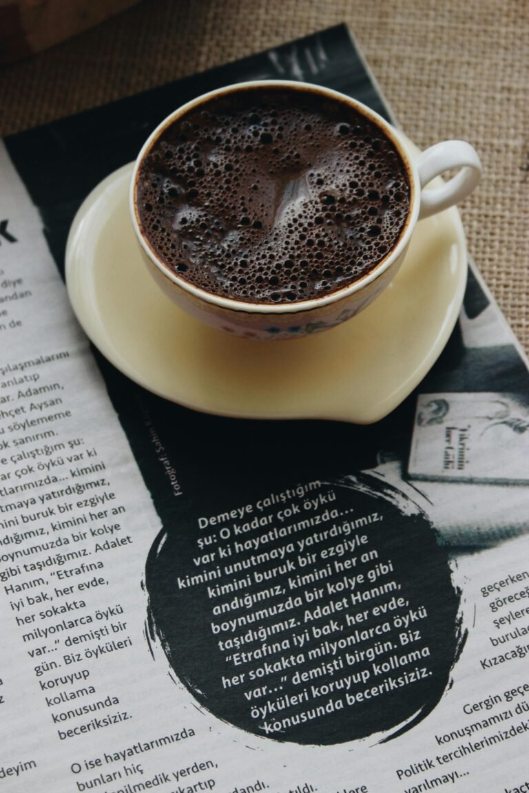 A cup of hot Turkish coffee on a saucer placed on Turkish text in a cozy setting.