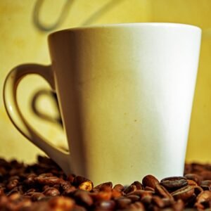 A white coffee mug surrounded by aromatic coffee beans, perfect for a cozy ambiance.